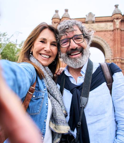Vertical portrait happy senior tourist couple taking selfie outdoors in historical city. Vertical portrait happy senior tourist couple taking selfie outdoors in historical city. Smiling elderly people traveling together on vacation. Cheerful man and woman posing for photo mobile phone.